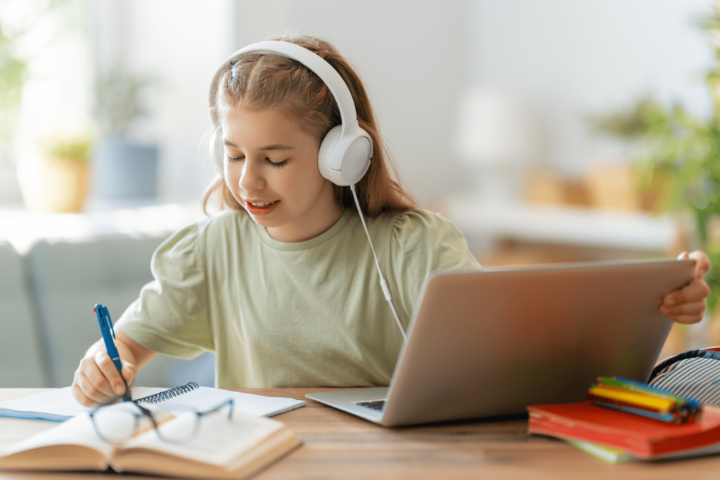 a girl is listening with her headphones while working on her laptop.